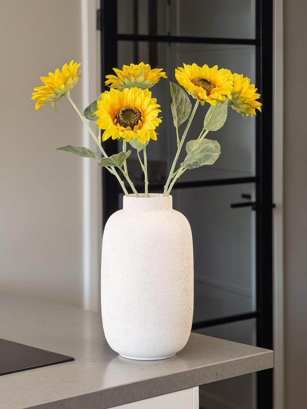 5 zonnebloemen in vaas in een keuken