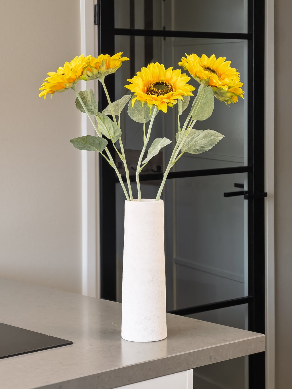 5 zonnebloemen in een smalle vaas op keukeneiland