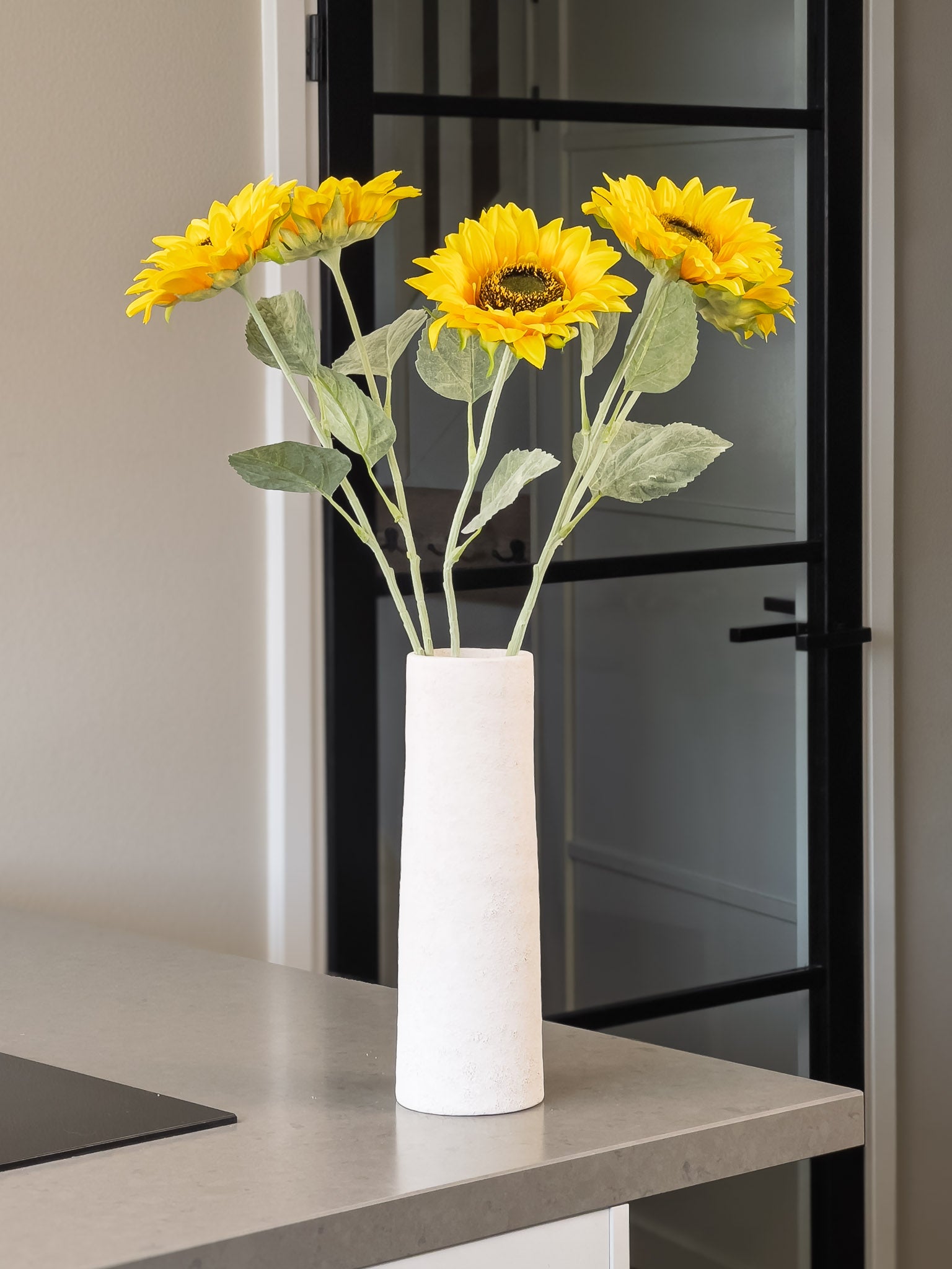 5 zonnebloemen in een smalle vaas op keukeneiland